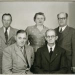 Svartvitt studio foto på fyra män och en kvinna.