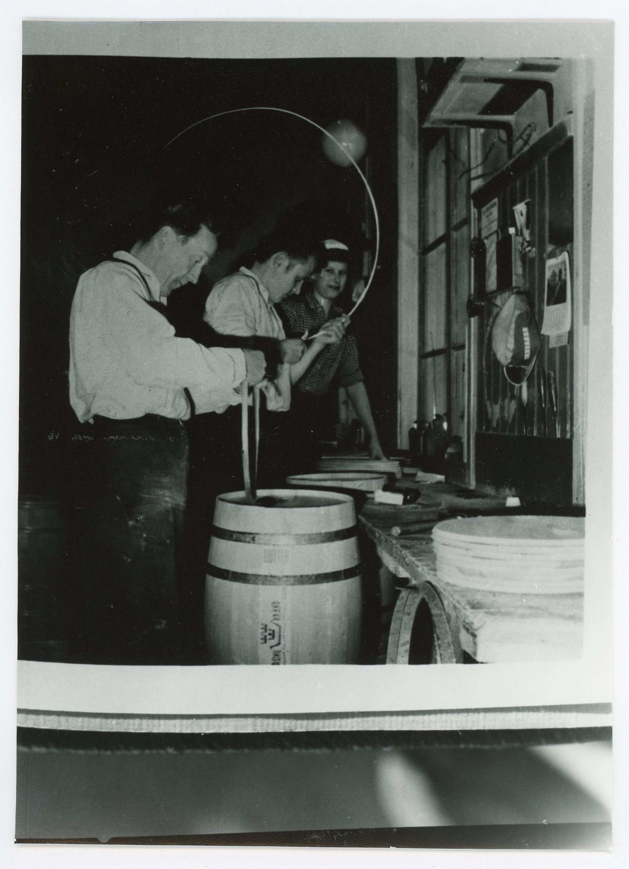 Tre män arbetar med att binda tunnar i en snickeriverkstad.